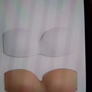 Två bandeau-bh - Säljer två bandeau-bhs i stilrena färger. Den ena är vit och den andra är beige. Dem ät i storlek 34 och har prislappen och förpackning kvar, aldrig använda!