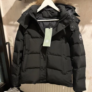Canada Goose jacka  - Hej säljer nu denna ÄKTA!! Exklusiva och stilrena vinterjackan, en Canada Goose Wyndham Parka black label. Jackan är helt ny och endast provad, jackan är designad för att ge både värme och snygg stil. Ett perfekt val för dig som vill ha en jacka som både är bekväm och ser bra ut hela vintern!   Jackan är köpt för 20 000kr på Canada goose hemsida och kvitto finns tillgänglig vid förfrågan. 