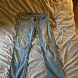 Acne Jeans - Snygga ljusblå jeans från Acne med klassisk femficksdesign och knappgylf. Perfekta för en avslappnad stil. Märkeslogga synlig på baksidan.