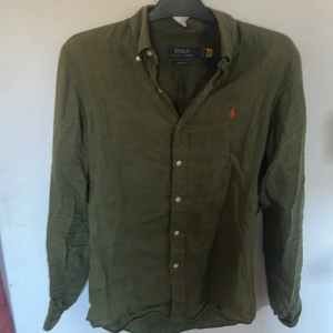 Olivgrön linneskjorta från Polo Ralph Lauren - Säljer en mörkgrön Ralph lauren skjorta som är perfekt till sommarn passar till massor av plagg!   Jag är storlek S/M och den passar mig bra 