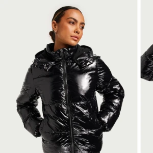 Svart glansig pufferjacka - Snygg svart glansig pufferjacka med dragkedja och huva från Nelly. Den är varm och perfekt för vinter. Säljer den då den knappt kommit till användning och tar plats. Kom privat för privata bilder eller frågor. 