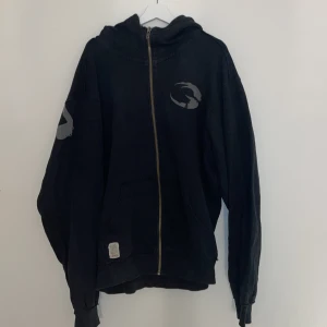 Svart hoodie från GASP - Säljer en svart hoodie från GASP i storlek XL. Den har en dragkedja framtill och tryck på både fram- och baksidan. Den har bra skick och är inte jätteanvänd. (Nypris 1000kr)