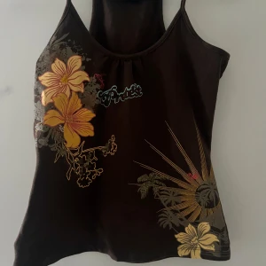 Brun linne med blommönster - Snygg brun linne med stora gula blommor🌼i mitten av blommorna är det påsydda små pärlor. Aldrig använt nyskick💗pris kan diskuteras 