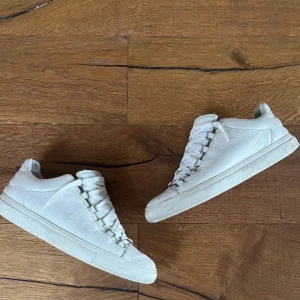 Balenciaga Arena vita  - Säljer ett par vita sneakers från Balenciaga i skinn. De har en klassisk design med snörning och är i bra skick. (bild 2 e gammal har tvättat dom) hmu för frågor!!