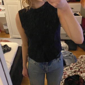 Svart ärmlös topp med spetsdetaljer - Säljer en elegant svart ärmlös topp med vackra spetsdetaljer. Perfekt för både vardag och festliga tillfällen. Toppen har en tight passform och är gjord i ett mjukt material som känns skönt mot huden. Passar perfekt till jeans eller kjol för en stilren look.