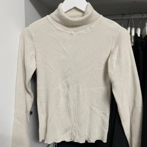 Beige ribbad polotröja - Säljer en superfin beige polotröja i ribbat material från 157. Perfekt för höst och vinter med sin mysiga och stilrena design. Tröjan har långa ärmar och en bekväm passform som passar till alla tillfällen. Ett måste i garderoben! 🍂