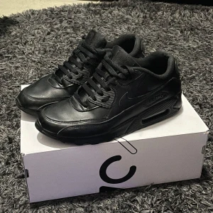 Läder Air Max 90 - Ett par svarta läder Air Max 90 i storlek 43, skorna är i okej skick då de har haft sina bättre dagar och de har några defekter(se 4 o 5 bilden) men inget som påverkar själva användningen av skorna. Pris går att diskuteras.