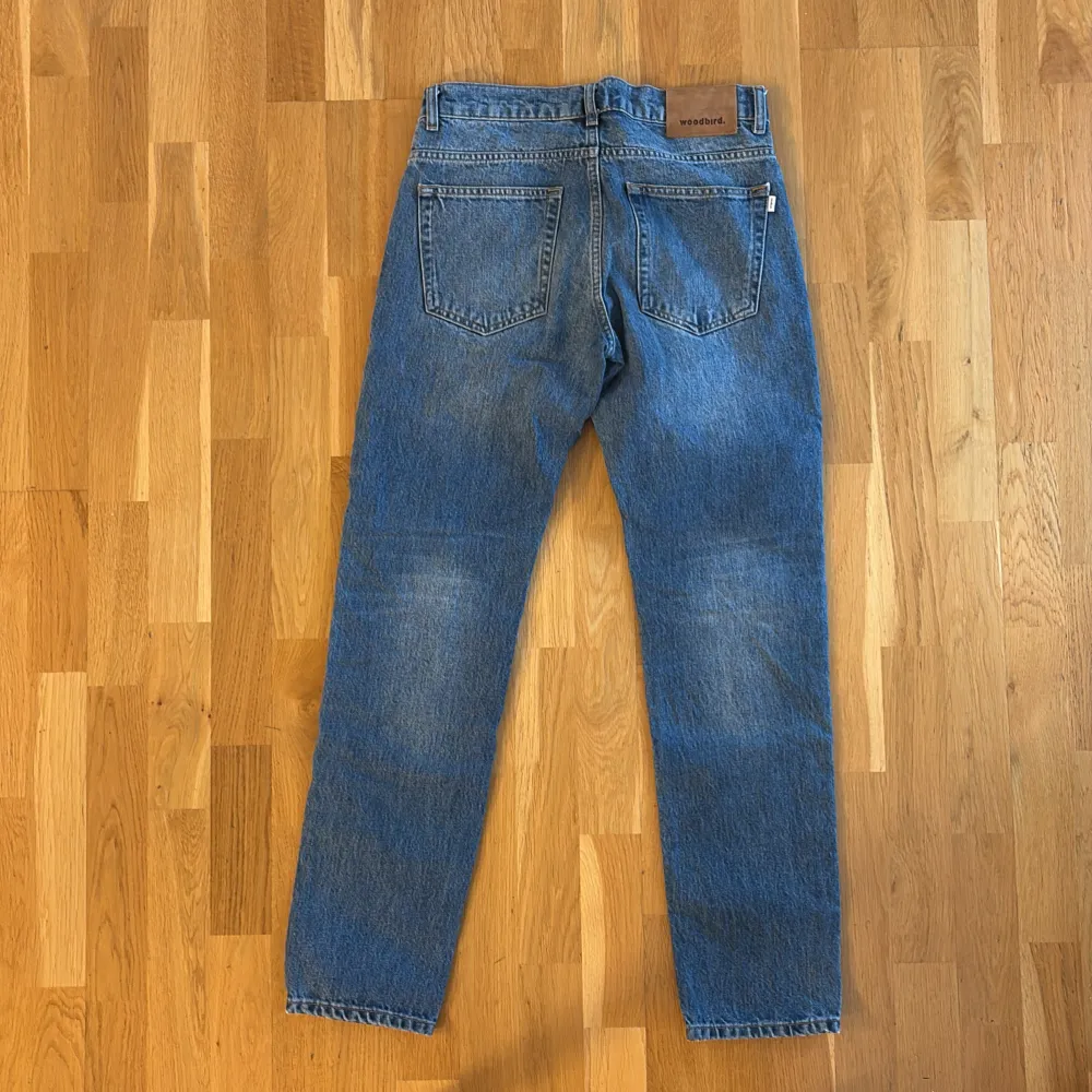 Säljer ett par snygga blå vintage jeans från Woodbird i storlek 29/32. De har en klassisk straight fit och är i mycket bra skick. Perfekta för både vardag och fest! 🕺. Jeans & Byxor.