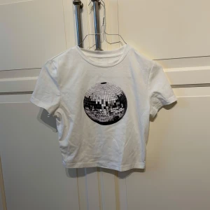 Vit t-shirt med discokultryck - Säljer en vit t-shirt med ett coolt discokultryck på framsidan. Den är croppad och kortärmad. 