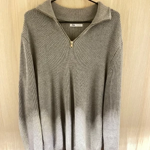 Grå stickad tröja från Zara - Säljer en snygg grå stickad tröja från Zara i storlek M. Den har en dragkedja framtill och en hög krage som ger en stilren look. Perfekt för kyliga höst- och vinterdagar. Tröjan är i mycket bra skick och supermjuk!