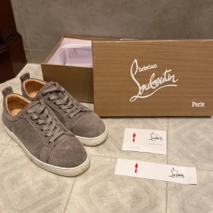 Grå loubs utan spikar - Säljer ett par snygga grå sneakers från Christian Louboutin i mocka. De har den ikoniska röda sulan och är i mycket bra skick. Perfekta för både vardag och fest! Skorna har snörning och en bekväm passform. Hör av er i DM vid frågor. Vet inte om dem är äkta därför säljes billigt. Box tags kvitto osv medföljer. Pruta vid snabb affär annars skitsamma😁