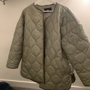Olivgrön quiltad jacka  - Säljer en olivgrön quiltad jacka från bik bok. Den har en oversized passform och är perfekt för höst och vår. Jackan har långa ärmar och knappar framtill. Den är superbekväm och lätt att stylea! Storlek M men är mer som en blandning mellan S och M