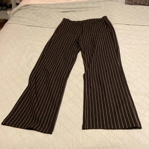 Svart- och vitrandiga byxor från Kappahl - Snygga svart- och vitrandiga byxor från Kappahl i storlek 164. De har en klassisk look med raka ben och hög midja. Perfekta för både skola och till fint. Byxorna har knappar och dragkedja framtill för en säker passform. De kan justeras med gummiband i midjan. 