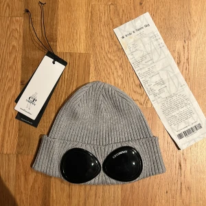 Grå mössa från C.P. Company - Hej, säljer nu min cp company mössa, jag har nästan aldrig använt den och skicket är 10/10 köpt på nk och man får med allt på bilderna