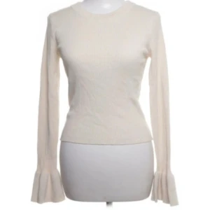 Beige ribbad tröja med volangärmar - Säljer en superfin beige ribbad tröja med unika volangärmar och en cool öppen rygg.  Perfekt för både vardag och fest! Tröjan är i mycket bra skick. Säljer då den inte kommer till användning. Hör av er vid frågor💕💕