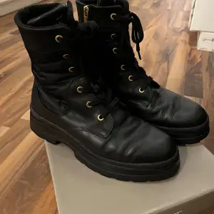 Säljer ett par snygga svarta boots från Gant i storlek 40. De är i skinn med snörning och dragkedja på sidan för enkel på- och avtagning. Perfekta för höst och vinter med en robust sula som ger bra grepp. Tillverkade i Portugal och i mycket bra skick.