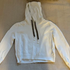 Vit hoodie från Zara Knit - Säljer en superfin vit hoodie från Zara Knit i storlek L. Den är i mycket bra skick och har snygga glittriga snören som ger en extra touch. Perfekt för höst och vår när du vill vara både bekväm och stilren. Passar till alla tillfällen!