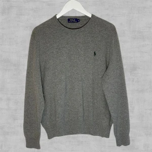 Ralph Lauren Tröja Merinoull - Ljusgrå stickad Ralph Lauren tröja i exklusivt merinoull i nyskick ”väcken på armarna är kvar” som intygar. Storlek ungdom XL och passar som S herr.  Ställ gärna frågor vid funderingar!