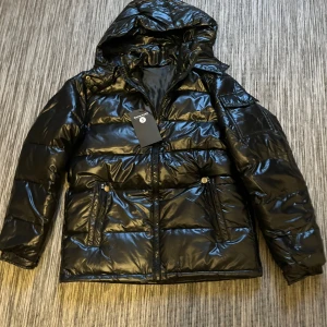 Glansig puffar jacka  - Glansig puffer jacka i herrmodell, storlek s. Aldrig använd, fortfarande har förpackningen och lappen på. 850kr
