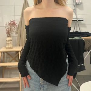 Svart off shoulder topp - Svart topp från asos med textur, asymetrisk fåll. Toppen är aldrig använd. Prislapp sitter kvar.  Toppen är i polyester och elastan