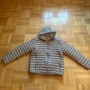 Save The Duck Donald Hooded Jacka - Underbart lätt att bära, medan den fortfarande isolerar bra Isolerad med en teknisk fiber som heter Plumtech Yttyg: 20 denier nylon, bluesign certifierad Tyget torkar snabbt när det behövs Skyddande krage Tvåvägs dragkedja Två fickor