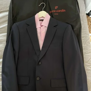 Kostym - Kostym set med marinblå kavaj & kostymbyxor. Märke: Pierre Cardan Size 44R (chest 42-44) (waist 34-40) Rosa Skjorta medföljer: strl S