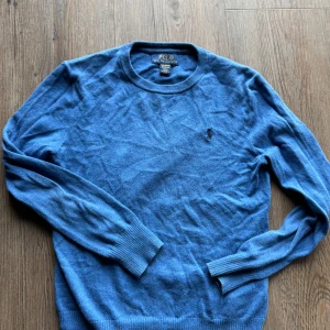 Blå tröja från Polo Ralph Lauren - Säljer en snygg blå tröja från Polo Ralph Lauren i storlek M. Den är gjord av mjuk pima bomull och har långa ärmar. Perfekt för både vardag och lite finare tillfällen. Tröjan har en klassisk design med ribbade muddar och nederkant. Passar perfekt till höst och vår!