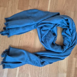Halsduk Calvin Klein - Halsduk från märket Calvin Klein. Turkos/havsblå färg. Väldigt mjuk och len material. Små fransar på vardera sida. 180 cm lång och 70 cm bred. Använd fåtal gånger. Viskos material. 