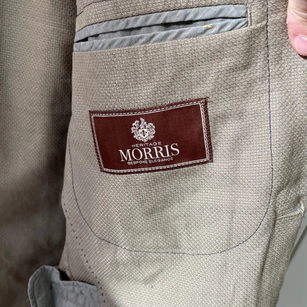 Säljer en snygg beige kavaj från Morris Heritage. Perfekt för sommaren med sin lätta blandning av bomull och linne. Kavajen har en klassisk design med två knappar fram och fickor. Den är i storlek 48 och passar perfekt för en stilren look.. Jackor.