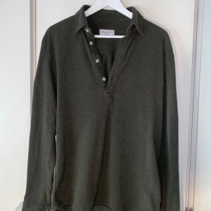 John Henric långärmad piké  - Grön långärmad bomulls piké, knappt använd som bara legat i garderoben. Storlek M men stor i storlek.