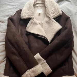 Brun jacka med foder - Säljer en varm höstjacka från H&M i mockaliknande material med vitt foder, perfekt nu till hösten! Inga defekter💕Har använts ett fåtal gånger och är lite oversized 