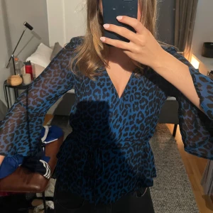 Mönstrad blus - Blå leopardmönstrad blus från Ganni med v-ringning, omlott och volanger i ärmarna!