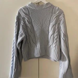 ljusblå stickad tröja ginatricot  - superfin ljusblå kabelstickad tröja från gina tricot. kort modell med långa större ärmar. har två lösa trådar på framsidan samt sminkfläckar vid kragen från tidigare säljaren.
