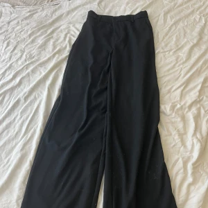 Svarta kostymbyxor  - Ett par svart högmidjade kostymbyxor.