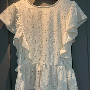 Vit topp från Vila - Vit fin topp från vila med fyrklövs håll i Volanger från axlarna o ner som en t-shirt och volanger ned till.