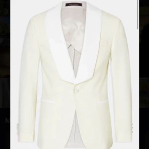 Vit kavaj från Oscar Jacobson - Säljer en elegant vit kavaj från Oscar Jacobson i samarbete med Lars Wallin. Kavajen har en stilren design med en bred krage och knappar framtill. Perfekt för formella tillfällen som bal eller fest. Materialet känns lyxigt och ger en snygg passform.