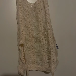 Beige stickad topp från ASOS - Säljer en superfin beige stickad topp från ASOS. Den är ärmlös och har en luftig, ribbad design som är perfekt för sommaren. Toppen är i storlek L och passar perfekt till både vardag och fest. Perfekt att matcha med jeans eller kjol för en avslappnad look!