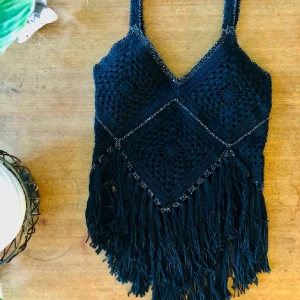 Svart virkat topp - Säljer en superfin svart virkad topp med fransar. Perfekt för sommarens festivaler eller en dag på stranden. Passar perfekt till shorts eller en kjol för en bohemisk look.