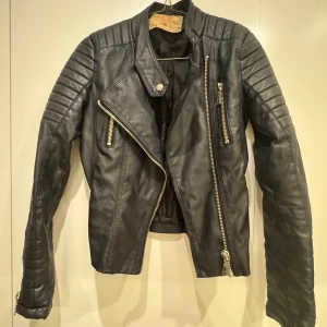 Skinnjacka från Chiquelle - Nyskick skinnjaska tight fitt från Chiquelle. Köpt för 800 kr (Nypris). Storlek 36 men passformen är för en storlek 34. Användes knappt. Inga repor eller skador på jackan. För frågor eller fler bilder skicka iväg ett meddelande :)