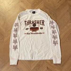 Långärmad tröja - En vit Trasher x Huf långärmad tröja, säljer då jag nästan aldrig använt så den är i nyskick. Snygg att ha under en tisha!