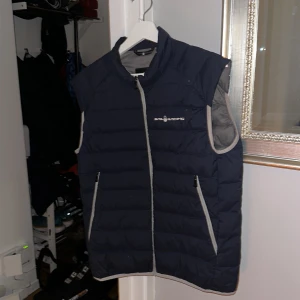 Sail Racing väst, M - Marinblå sailracing väst i storlek M, skicket är nästintill nyskick och sparsamt använd.