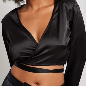 Silkestopp Nakd - Svart silkestopp från Nakd i storlek 38. Croppad med en snygg knytning runt midjan. Aldrig använd