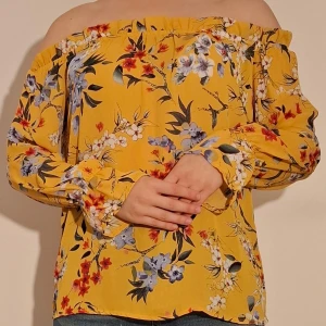 Gul off-shoulderblus med blomstermönster - Gul off-shoulderblus med blomstermönster.  (Sista bilden visar tröjans material)