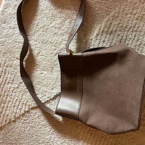 Höstig handväska  - Brun, helt ny, axelremsväska. Rymligt och perfekt att ha med sig överallt! Är i fejkmocka och fejkskinn med guldiga detaljer, super snygg everyday väska!✨