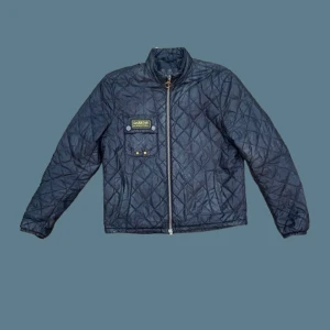 Svart quiltad jacka från Barbour - Säljer en snygg svart quiltad jacka från Barbour International. Den har en dragkedja framtill och en soft broderad logga på bröstet. Perfekt för höst och vår med sin stilrena design och bekväma passform. Jackan är i bra skick och använd varsamt. Kontakta oss gärna om du har någon fundering 🙏