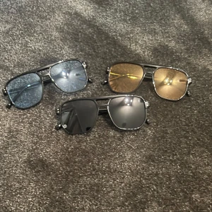 Tre par solglasögon i olika färger - Säljer tre par stiliga solglasögon med metallbågar. Ett par har blåtonade glas, ett par har guldfärgade glas och det sista paret har mörktonade glas. Perfekta för både sommar och vår, och ger en cool look till vilken outfit som helst. Alla glasögon har en klassisk design med en modern twist.