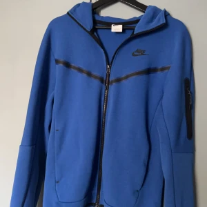 Blå Nike tech - Säljer denna blåa Nike tech väldigt OG i färgen eftersom den inte säljs längre skicket är 9/10 använda några gånger bara, inga defekter på att den är använd, säljs för 400kr
