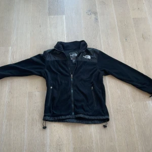 Svart fleecejacka från The North Face - Säljer en svart fleecejacka från The North Face, Summit Series. Jackan är i nyskick och har en dragkedja framtill. Den är perfekt för höst och vår, med långärmade ärmar och en skön passform. Materialet är fleece, vilket gör den både varm och bekväm. Perfekt för utomhusaktiviteter!