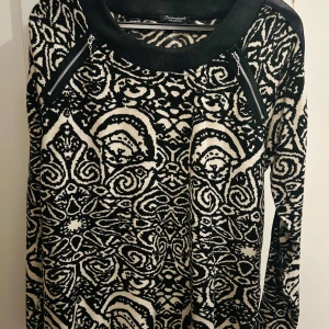 Svartvit mönstrad tröja från Brandtex - Säljer en snygg svartvit mönstrad tröja från Brandtex. Tröjan har ett unikt mönster och är långärmad med coola dragkedjedetaljer vid axlarna. Perfekt för både vardag och fest!