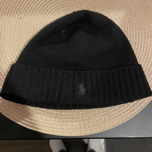 Svart Polomössa  - Säljer en polo mössa i nyskick. Den är helsvart med ett svart märke. Skriv om ni har några frågor. Priset går att diskutera:)